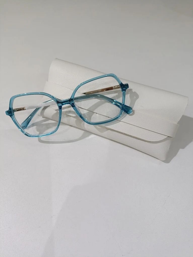 Armazón de acetato celeste translúcido apoyado sobre un estuche blanco